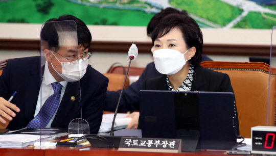 해법은…  김현미(오른쪽) 국토교통부 장관이 19일 국회 교통위원회 전체회의에서 윤성원 1차관과 대화를 하고 있다.   연합뉴스